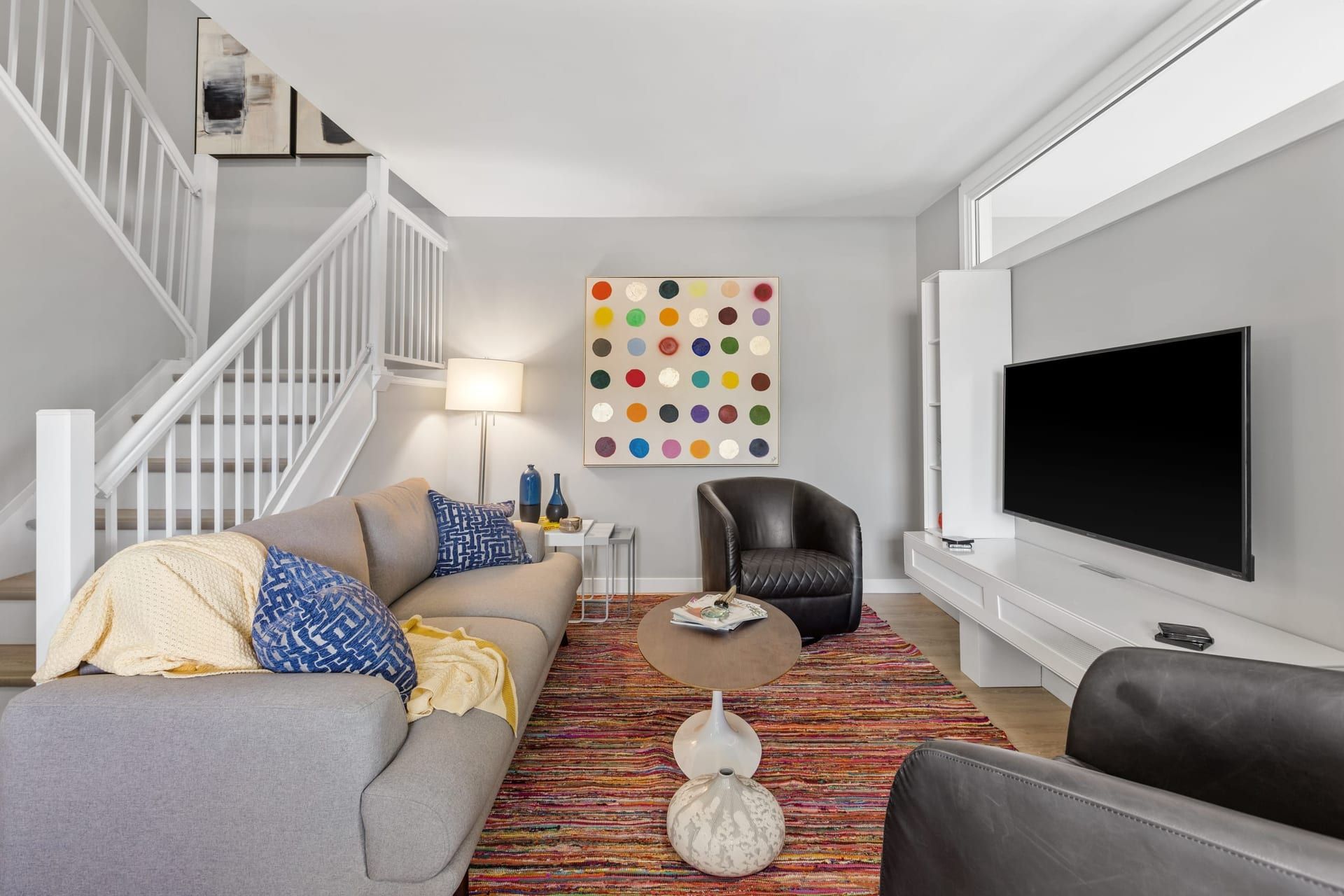 Woodroffe Towns: living room with sofa, swivel chair and the staircase rising behind, furnished townhouse in Nepean, Ottawa